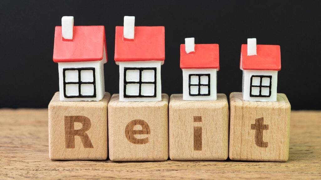 Reit, Real estate investment trust concept, miniature houses on cube wooden block with alphabet combine the word Reit on dark black background