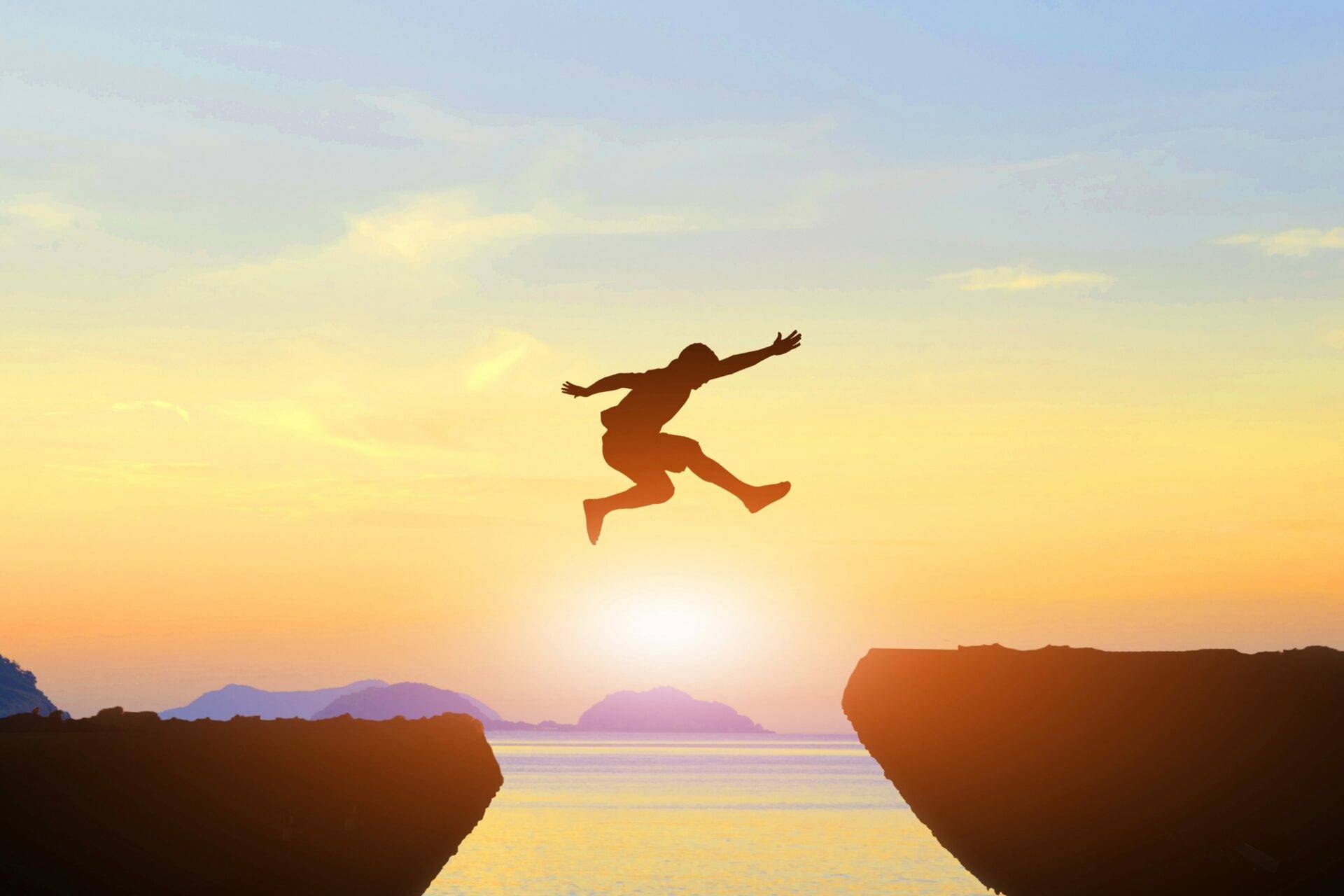 Man jumping over gap between two rock ledges, indicating the business plan gap for startup entrepreneurs' strategies